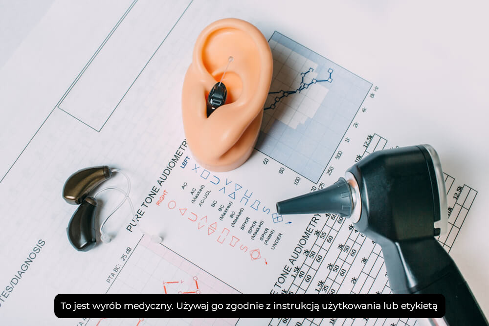 Proteza ucha, aparat słuchowy, wykres audiometryczny i otoskop na dokumentach medycznych.